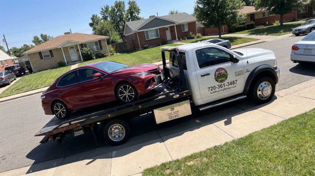 Dark red 2018 Toyota Camry loaded on an Auto Recycling Mile High tow truck at a cash-for-cars pickup in the Denver metro