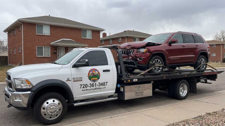 Dark red 2016 Jeep Grand Cherokee loaded on an Auto Recycling Mile High tow truck at a cash-for-cars pickup in the Denver metro