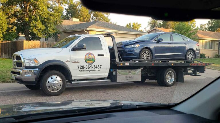 Dark blue 2017 Ford Fusion loaded on an Auto Recycling Mile High tow truck at a cash-for-cars pickup in the Denver metro