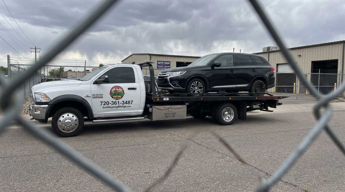Black 2017 Mitsubishi Outlander loaded on an Auto Recycling Mile High tow truck at a cash-for-cars pickup in the Denver metro
