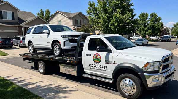 White 2024 Chevrolet Tahoe on an Auto Recycling Mile High flatbed tow truck during a cash-for-cars pickup in Colorado, Colorado