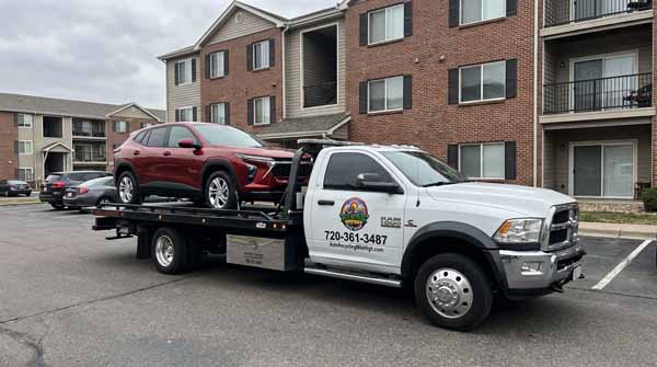 Red 2024 Chevrolet Trax on an Auto Recycling Mile High flatbed tow truck during a cash-for-cars pickup in Cherry Creek, Colorado