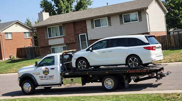 White 2024 Honda Odyssey on an Auto Recycling Mile High flatbed tow truck during a cash-for-cars pickup in Commerce City, Colorado