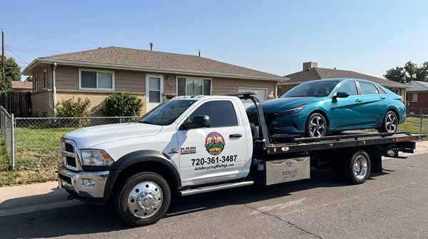 Teal 2024 Hyundai Elantra on an Auto Recycling Mile High flatbed tow truck during a cash-for-cars pickup in Commerce City, Colorado