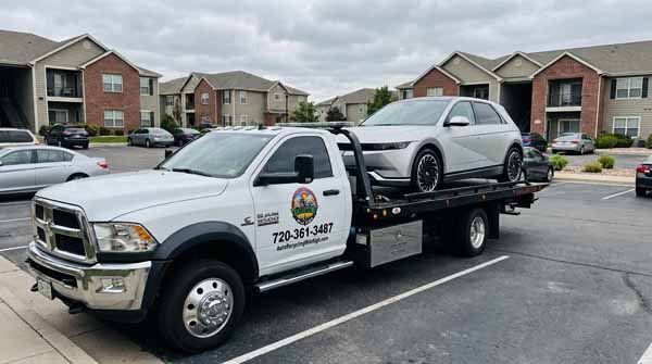 Silver 2024 Hyundai Ioniq 5 on an Auto Recycling Mile High flatbed tow truck during a cash-for-cars pickup in Greenwood Village, Colorado