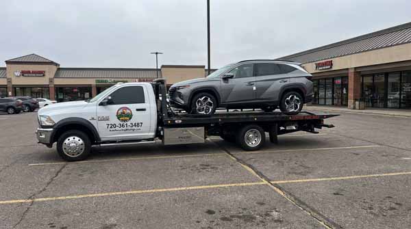 Gray 2024 Hyundai Tucson on an Auto Recycling Mile High flatbed tow truck during a cash-for-cars pickup in the Denver metro, Colorado