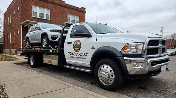Silver 2024 Jeep Grand Cherokee on an Auto Recycling Mile High flatbed tow truck during a cash-for-cars pickup in the Denver metro, Colorado