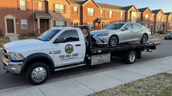 Silver 2024 Lexus ES 350 on an Auto Recycling Mile High flatbed tow truck during a cash-for-cars pickup in Denver, Colorado