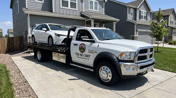 White 2024 Toyota Corolla on an Auto Recycling Mile High flatbed tow truck during a cash-for-cars pickup in Aurora, Colorado
