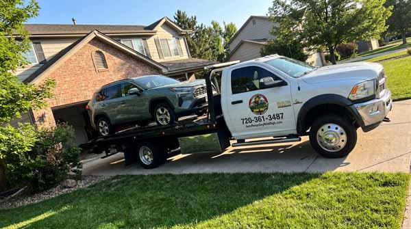 Green 2024 Toyota RAV4 on an Auto Recycling Mile High flatbed tow truck during a cash-for-cars pickup in Denver, Colorado