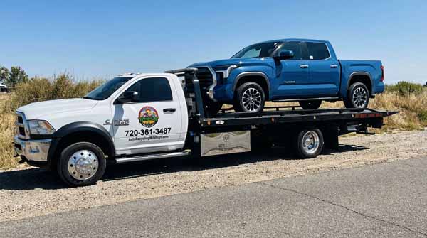 Blue 2024 Toyota Tundra on an Auto Recycling Mile High flatbed tow truck during a cash-for-cars pickup in Denver, Colorado