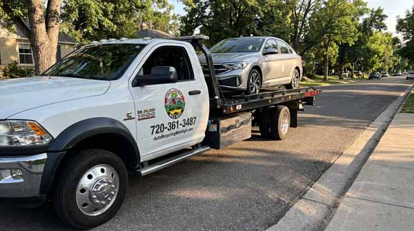 Silver 2024 Volkswagen Jetta on an Auto Recycling Mile High flatbed tow truck during a cash-for-cars pickup in Cherry Creek, Colorado