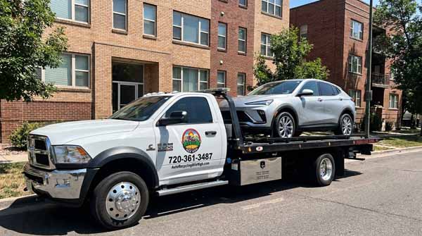 Silver 2025 Buick Envista on an Auto Recycling Mile High flatbed tow truck during a cash-for-cars pickup in Thornton, Colorado