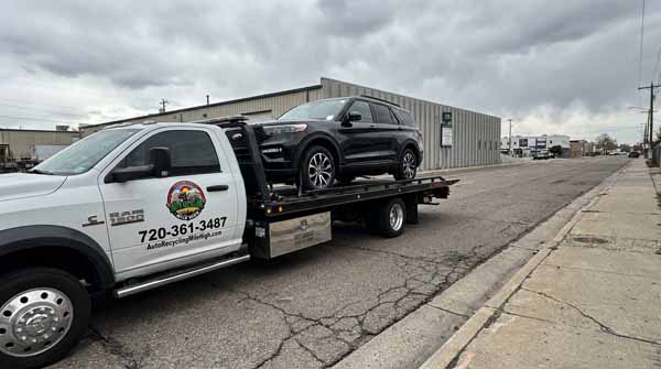 Black 2025 Ford Explorer on an Auto Recycling Mile High flatbed tow truck during a cash-for-cars pickup in Greenwood Village, Colorado