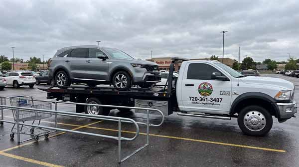Gray 2025 Kia Sorento on an Auto Recycling Mile High flatbed tow truck during a cash-for-cars pickup in Denver, Colorado