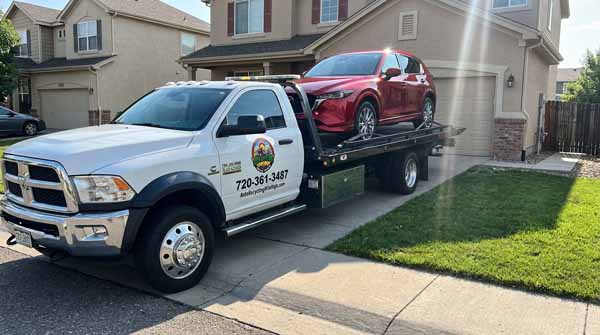 Soul red 2025 Mazda CX-5 on an Auto Recycling Mile High flatbed tow truck during a cash-for-cars pickup in Littleton, Colorado