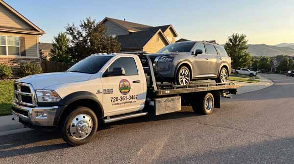 Gray 2025 Nissan Pathfinder on an Auto Recycling Mile High flatbed tow truck during a cash-for-cars pickup in Commerce City, Colorado