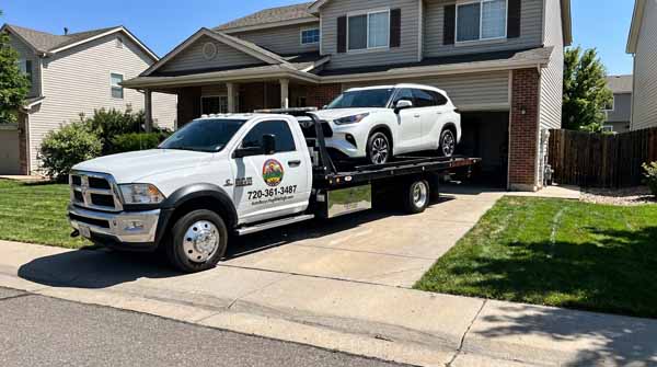 White 2025 Toyota Highlander on an Auto Recycling Mile High flatbed tow truck during a cash-for-cars pickup in Colorado, Colorado