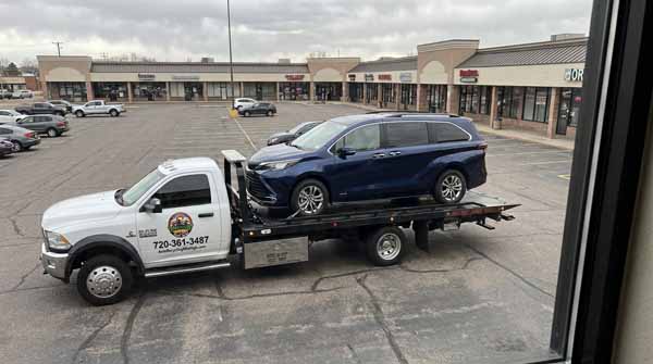 Dark blue 2025 Toyota Sienna on an Auto Recycling Mile High flatbed tow truck during a cash-for-cars pickup in the Denver metro, Colorado