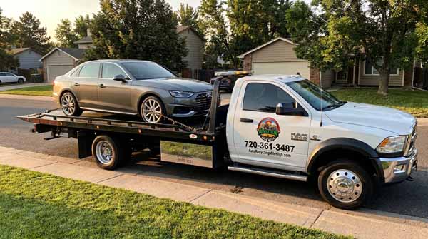 Gray 2026 Audi A4 on an Auto Recycling Mile High flatbed tow truck during a cash-for-cars pickup in Colorado, Colorado